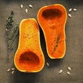 Halves of raw pumpkin or butternut squash with herbs for cooking on parchment paper. Top view, flat lay