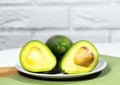 Halves of Ripe Avocado on bowl served on table, Green and white background, Healthy oily food, Keto diet