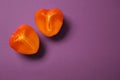 Halves of ripe persimmon on color background
