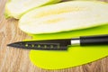 Halves of squash marrow and knife on plastic cutting board on table