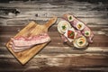 Ham And Cheese and Cherry Tomato Sandwich with Bacon Rashers on Cutting Board, set on Old Wooden Garden Table Surface Royalty Free Stock Photo