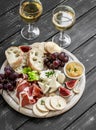 Ham, cheese, grapes, figs, nuts, bread ciabatta, cracker, jam on white wooden board on bright wooden surface. Rustic style. Royalty Free Stock Photo