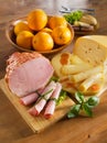 Ham, cheese, loaf and oranges on a kitchen table.