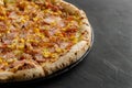 Ham and corn pizza prepared in a wood-fired oven