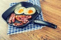 Ham and Egg. Bacon and Egg. Salted egg and sprinkled with black pepper. Grilled bacon, two eggs in a Teflon pan Royalty Free Stock Photo