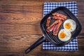 Ham and Egg. Bacon and Egg. Salted egg and sprinkled with black pepper. Grilled bacon, two eggs in a Teflon pan Royalty Free Stock Photo