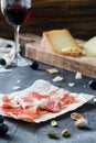 Ham jamon serrano or prosciutto crudo with sliced hard cheeses glass of red wine with grapes, pistachios Royalty Free Stock Photo