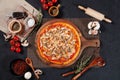 Ham and Mushroom Pizza with raw cherry tomato, black pepper, garlic, and mushroom isolated on wooden cutting board on dark Royalty Free Stock Photo