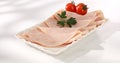 ham with cherry tomato on a plate. meat delicacy on a light background. turkey ham slices with parsley. cold appetizer Royalty Free Stock Photo