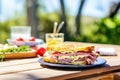 ham and swiss sandwich with a bite taken out on a picnic table