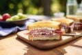 ham and swiss sandwich with a bite taken out on a picnic table