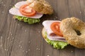 Ham , tomato, green lettuce leaf on round sesame bun, 2 sandwiches on wooden background
