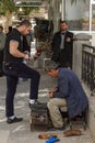 An elderly Syrian Shoe shiner is polishing a young man's shoes on his shoeshine box