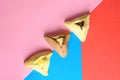 Hamantash filled-pocket cookie recognizable for triangular shape for Jewish holiday of Purim on red and blue background.