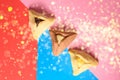 Hamantash filled-pocket cookie recognizable for triangular shape for Jewish holiday of Purim on red and blue background.