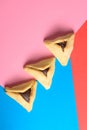 Hamantash filled-pocket cookie recognizable for triangular shape for Jewish holiday of Purim on red and blue background.