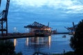 Lluminated Container Ship / Freighter at Dusk in the port of Hamburg with big Gantry Cranes Container Cranes. Harbor Tour Boat