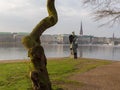 View at tree and sculpture named Windsbraut, whirlwind and Binnenalster in Hamburg, Germany.