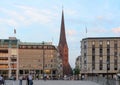 View of building and Church of Saint Peter bell tower at Kleine Alster in summer with crowd of people on street