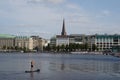 Man standing on a stand up paddle board is paddling on Binnenalster in Hamburg.