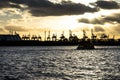 Hamburg harbor at sunset with little ship on river and cranes in background Royalty Free Stock Photo