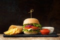 Hamburger with beef, french fries, sauces on a dark background. Fast food, burger Royalty Free Stock Photo