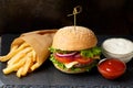 Hamburger with beef, french fries, sauces on a dark background. Fast food, burger Royalty Free Stock Photo