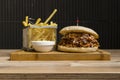 Hamburger with cheese and fried potatoes on a wooden table