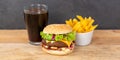 Hamburger Cheeseburger meal fastfood fast food with cola drink and French Fries on a wooden board panorama Royalty Free Stock Photo
