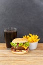 Hamburger Cheeseburger meal fastfood fast food with cola drink and French Fries on a wooden board portrait format Royalty Free Stock Photo