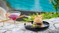 Hamburger and a cocktail at lunch at a restaurant looking out over the swimming pool