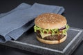 Hamburger with a double serving of meat, tomatoes, salad, onions on a wooden board in a restaurant.Copy space