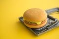 Hamburger fast food in a rat trap on yellow background copy space. Junk foods, unhealthy, people office lifestyle concept. Royalty Free Stock Photo