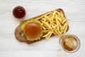 Hamburger, french fries, bbq sauce and glass of cold beer on a white wooden background, top view. Close-up Royalty Free Stock Photo