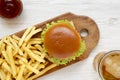 Hamburger, french fries, bbq sauce and glass of cold beer on a white wooden background, top view. Overhead, flat lay, from above Royalty Free Stock Photo