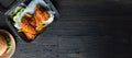 Hamburger, french fries and fried chicken in takeaway containers on the wooden background. Food delivery and fast food concept.