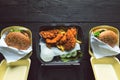 Hamburger, french fries and fried chicken in takeaway containers on the wooden background. Food delivery and fast food concept Royalty Free Stock Photo