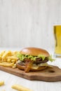 Hamburger, french fries and glass of cold beer on a white wooden background, side view. Close-up Royalty Free Stock Photo