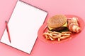 Hamburger with french fries in the plate and clipboard on pink Royalty Free Stock Photo