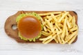 Hamburger and french fries on a rustic wooden board on a white wooden background, top view Royalty Free Stock Photo