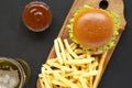 Hamburger, french fries, sauce and glass of cold beer on a black background, top view. Flat lay, from above, overhead Royalty Free Stock Photo