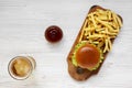 Hamburger, french fries, sauce and glass of cold beer on a white wooden background, top view. Overhead, flat lay, from above Royalty Free Stock Photo