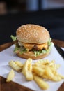 Hamburger with french fries served on a wooden plate. Royalty Free Stock Photo