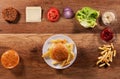 Hamburger ingredients on wooden table with an assembled burger i