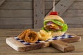 Hamburger, onion ring and french fries on chopping board