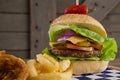 Hamburger, onion ring and french fries on chopping board