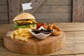 Hamburger, onion ring and french fries on chopping board