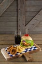 Hamburger, onion ring and french fries with cold drink on chopping board