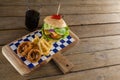 Hamburger, onion ring and french fries with cold drink on chopping board