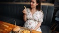Hamburger pregnancy girl eat. Pretty happy pregnant woman eating tasty burger. Junk food concept. Royalty Free Stock Photo